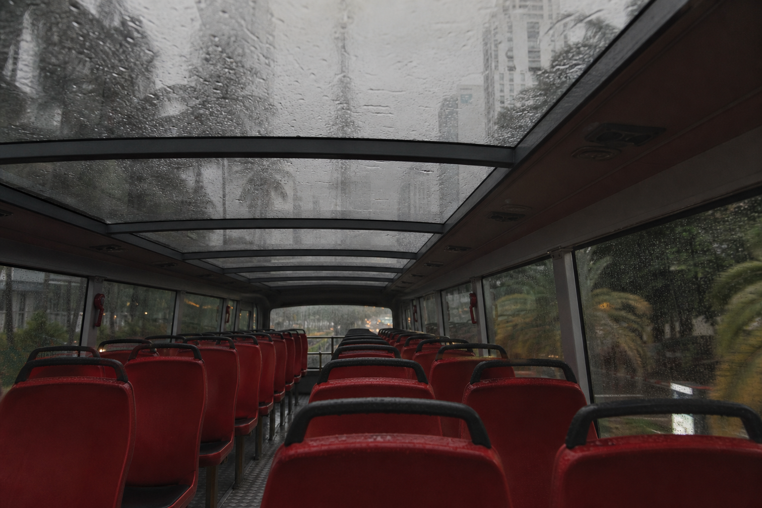 Glass panels, not open air. The upper deck is the one seat in the city that keeps working through a squall.